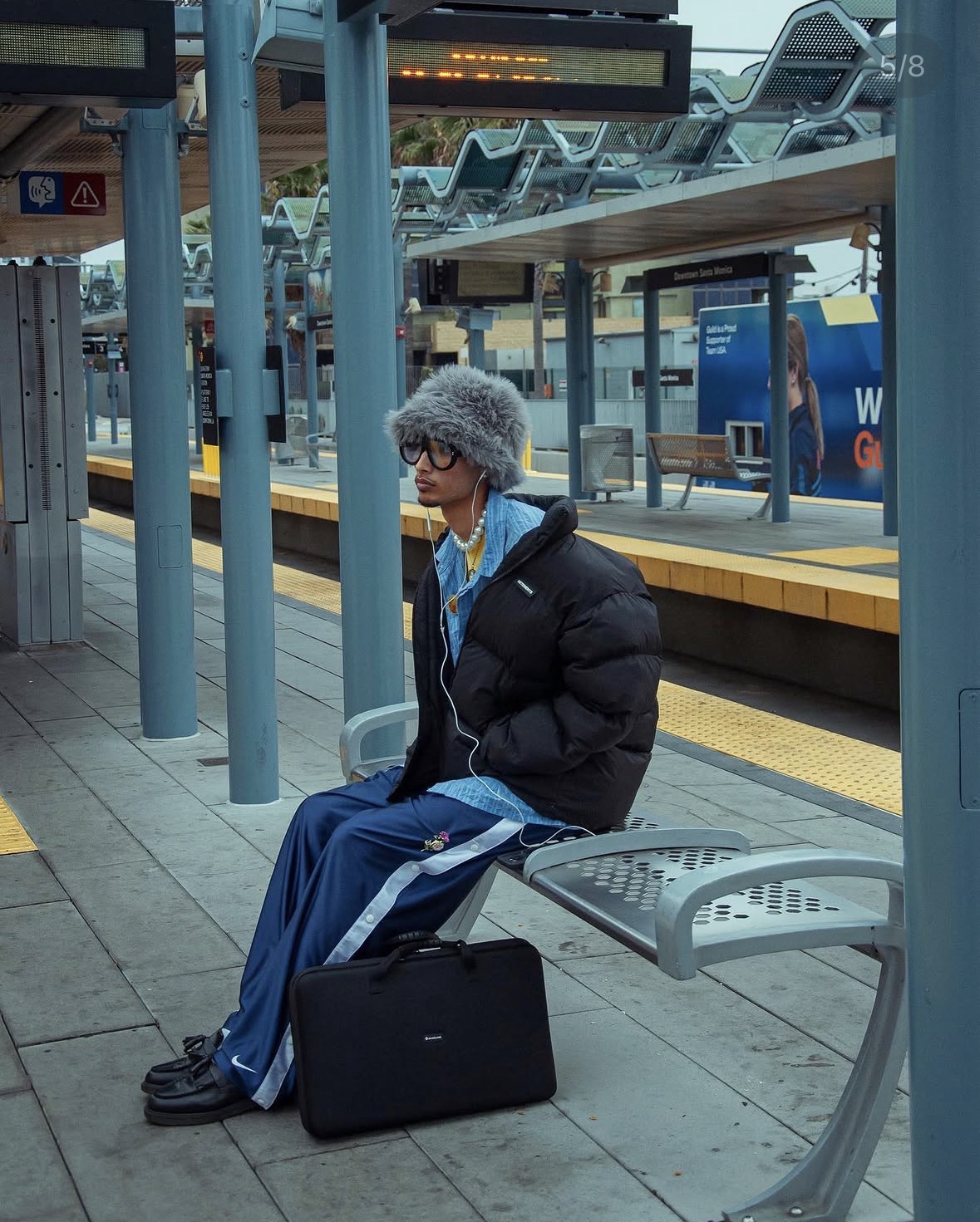 Model seated on a Metro platform in layered streetwear