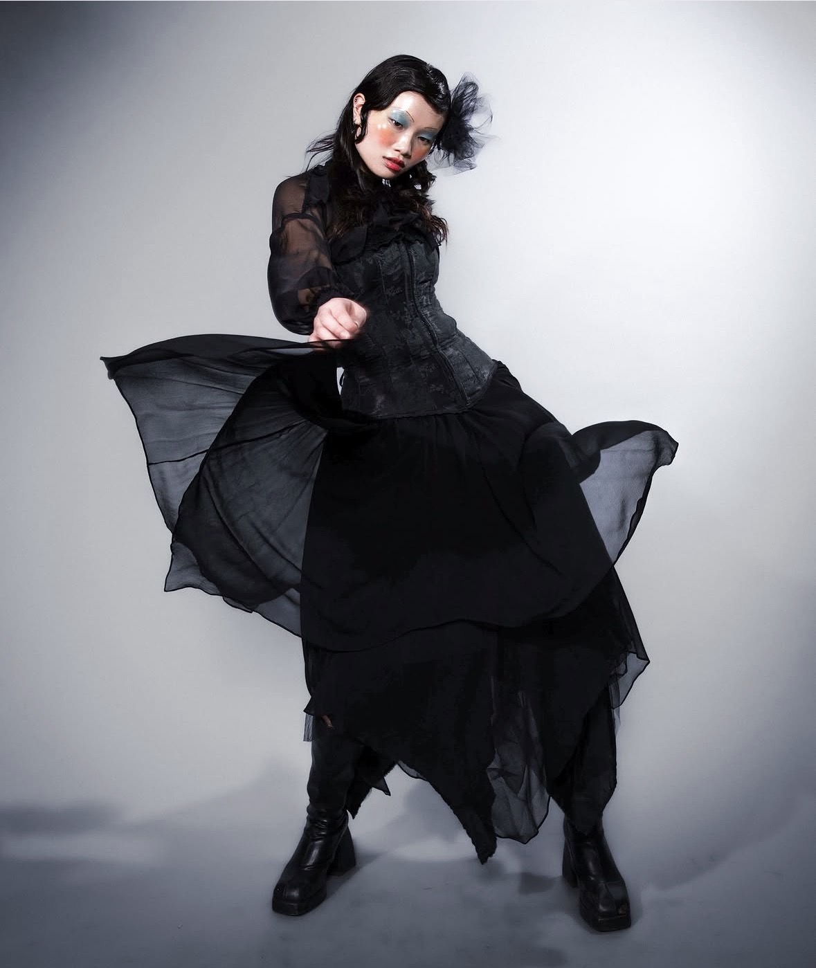 Model moving in a layered black gown with a handmade tulle headpiece